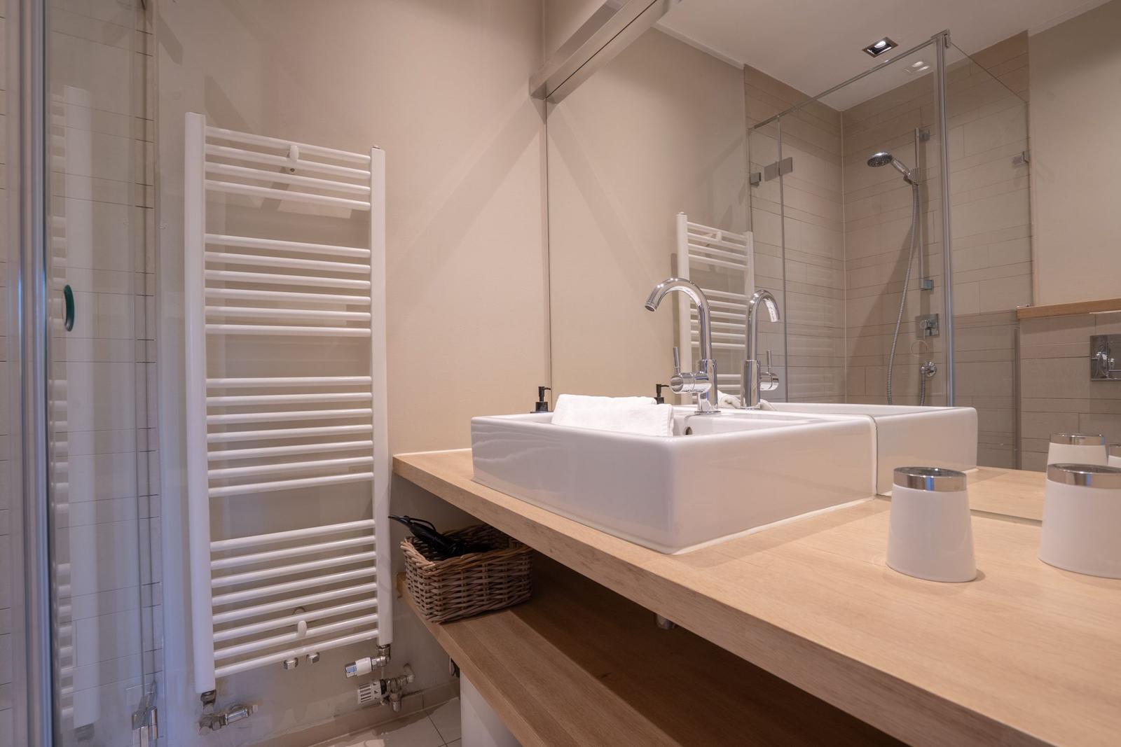 Badezimmer mit Waschbecken, Spiegel und Dusche