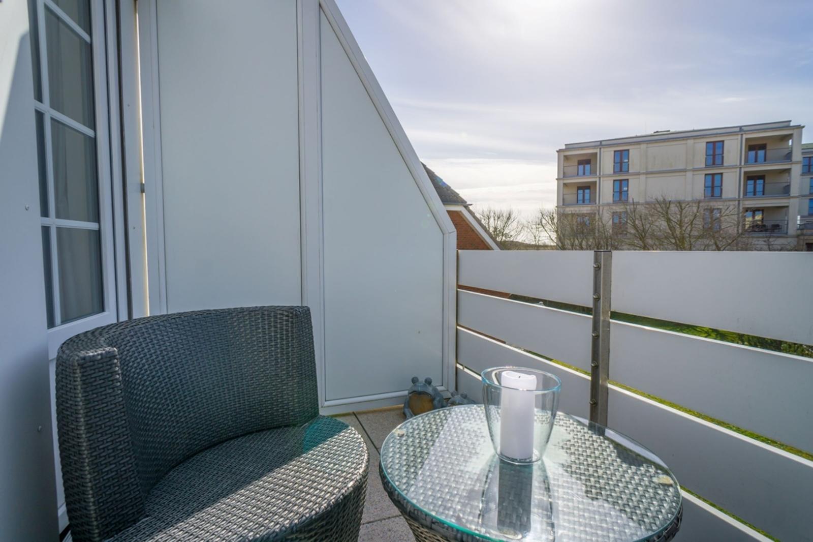 Terrace with chair and table. Background: buildings and fence.