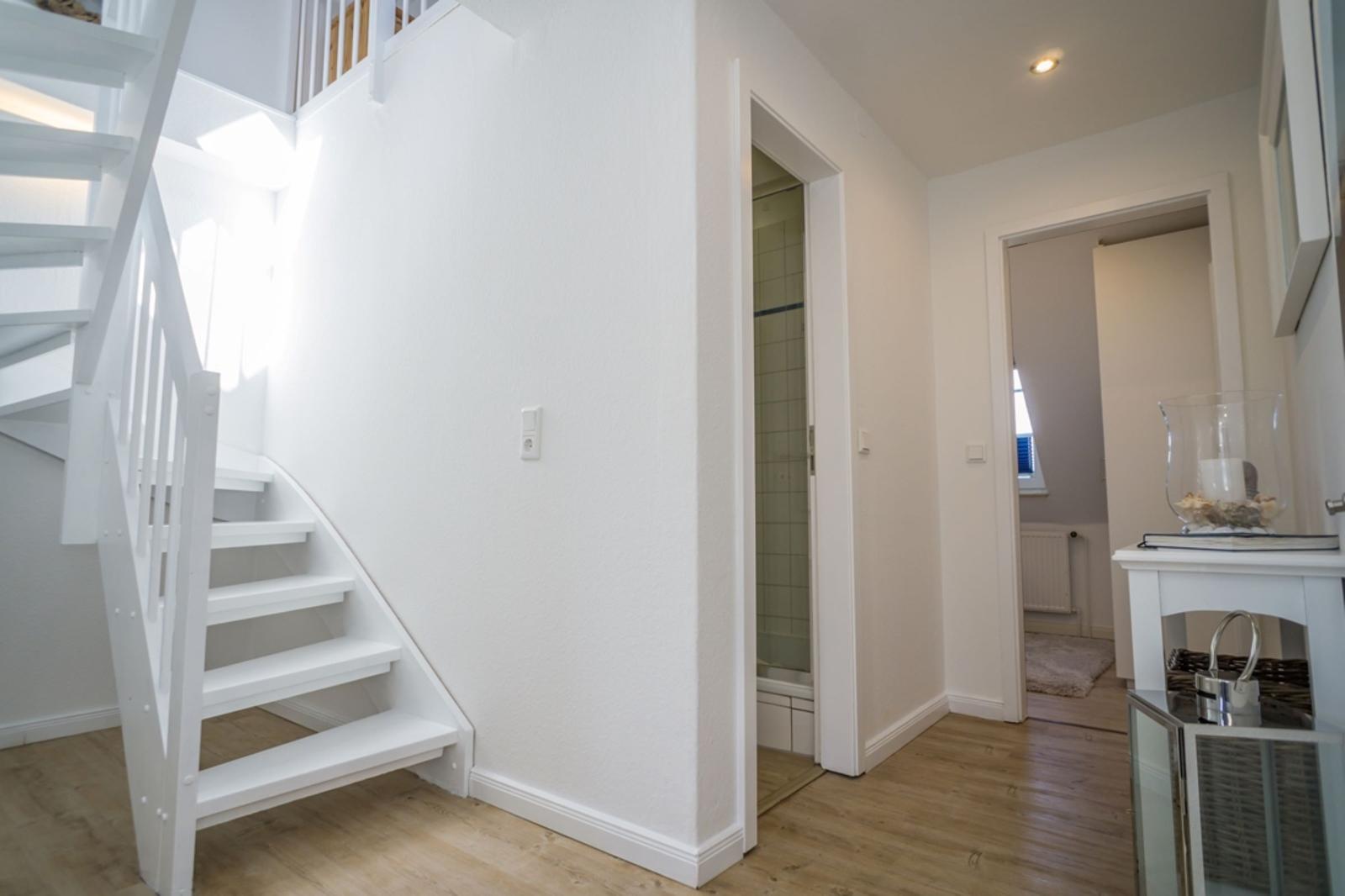 Bright entryway with staircase and view into bathroom and bedroom.
