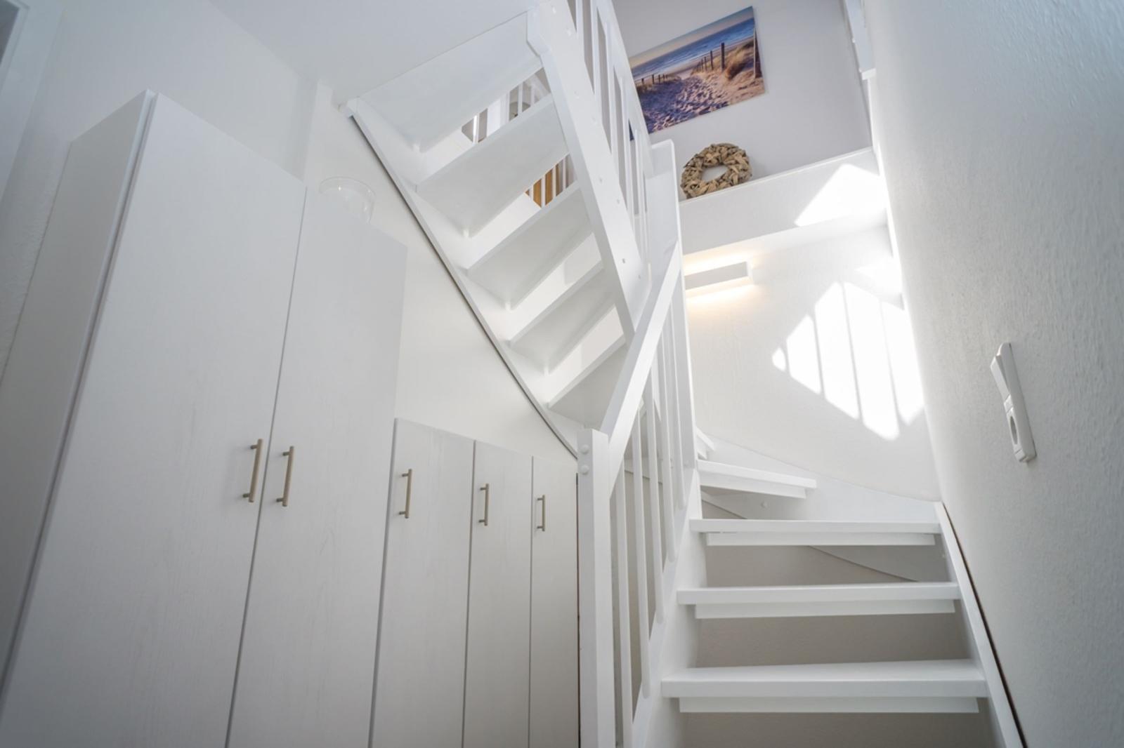 White staircase with closet and wall art in hallway
