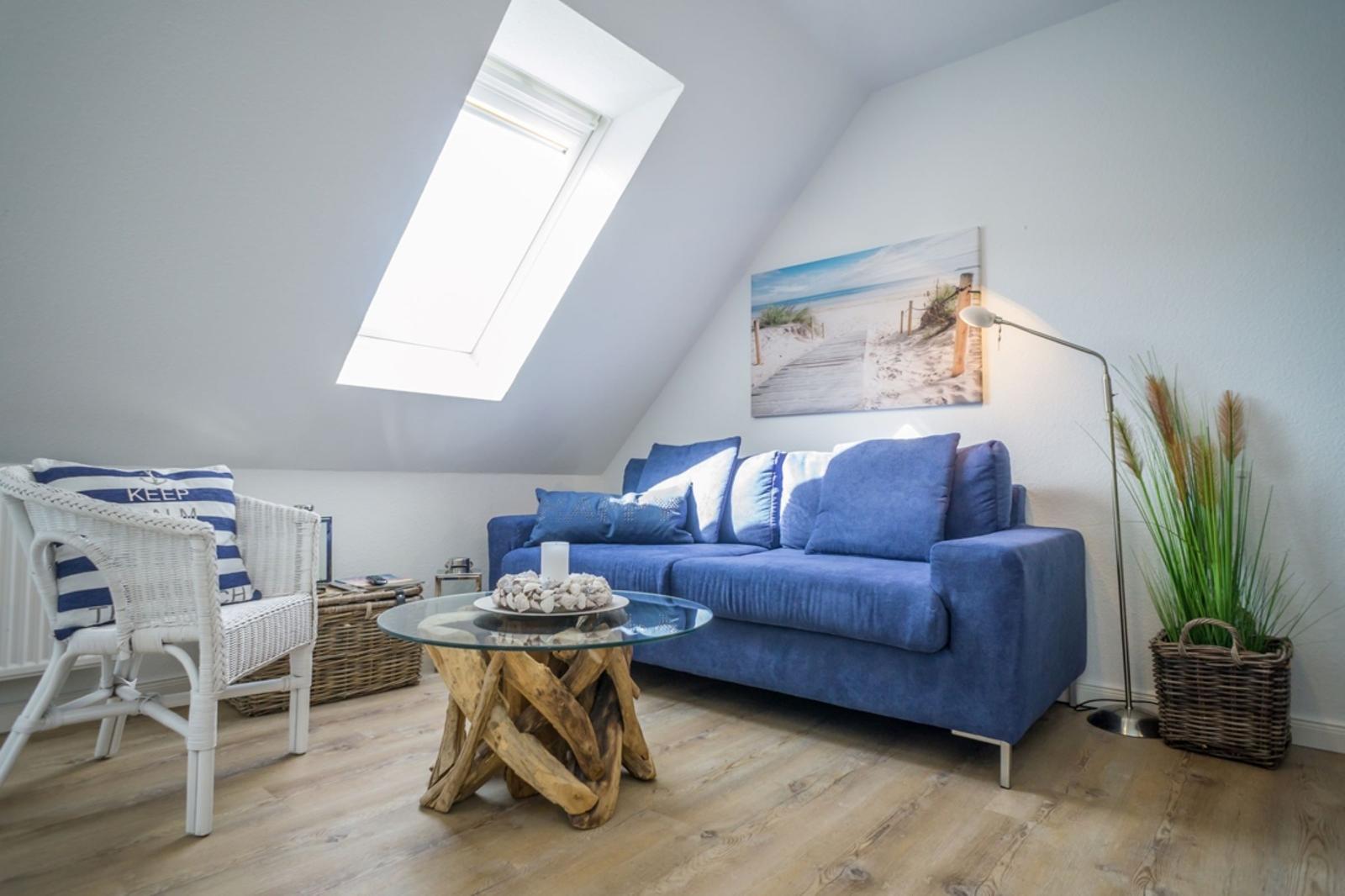 Living room with blue sofa, white chair, and skylight.
