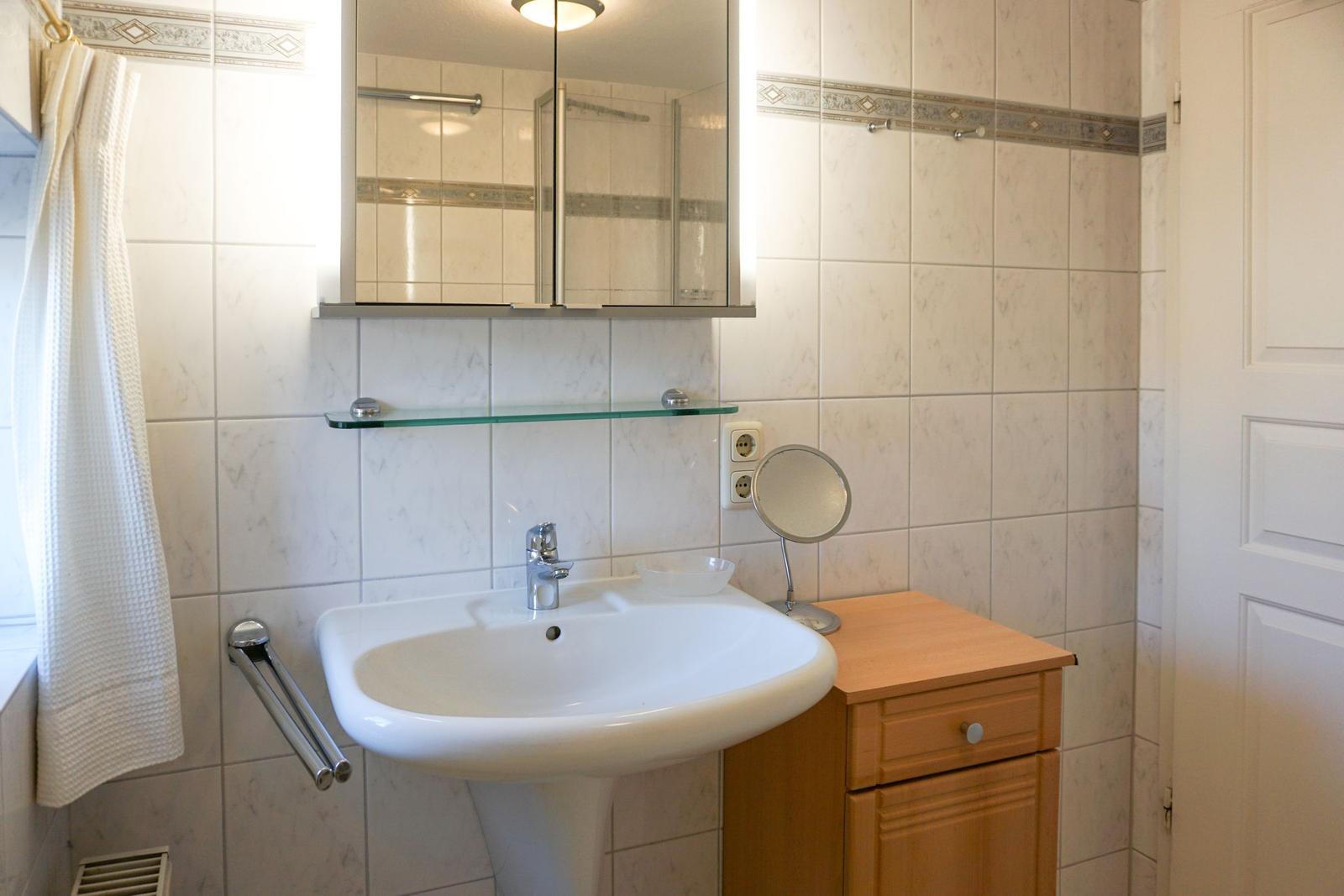 Bathroom with sink, mirror, and wooden cabinet.