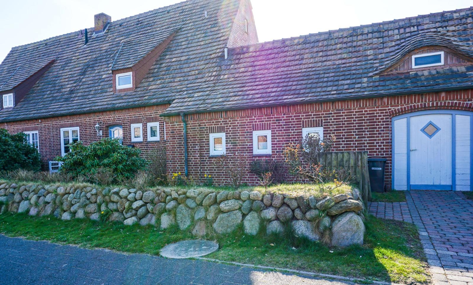 Red brick building with slate roof and stone wall in the front garden.