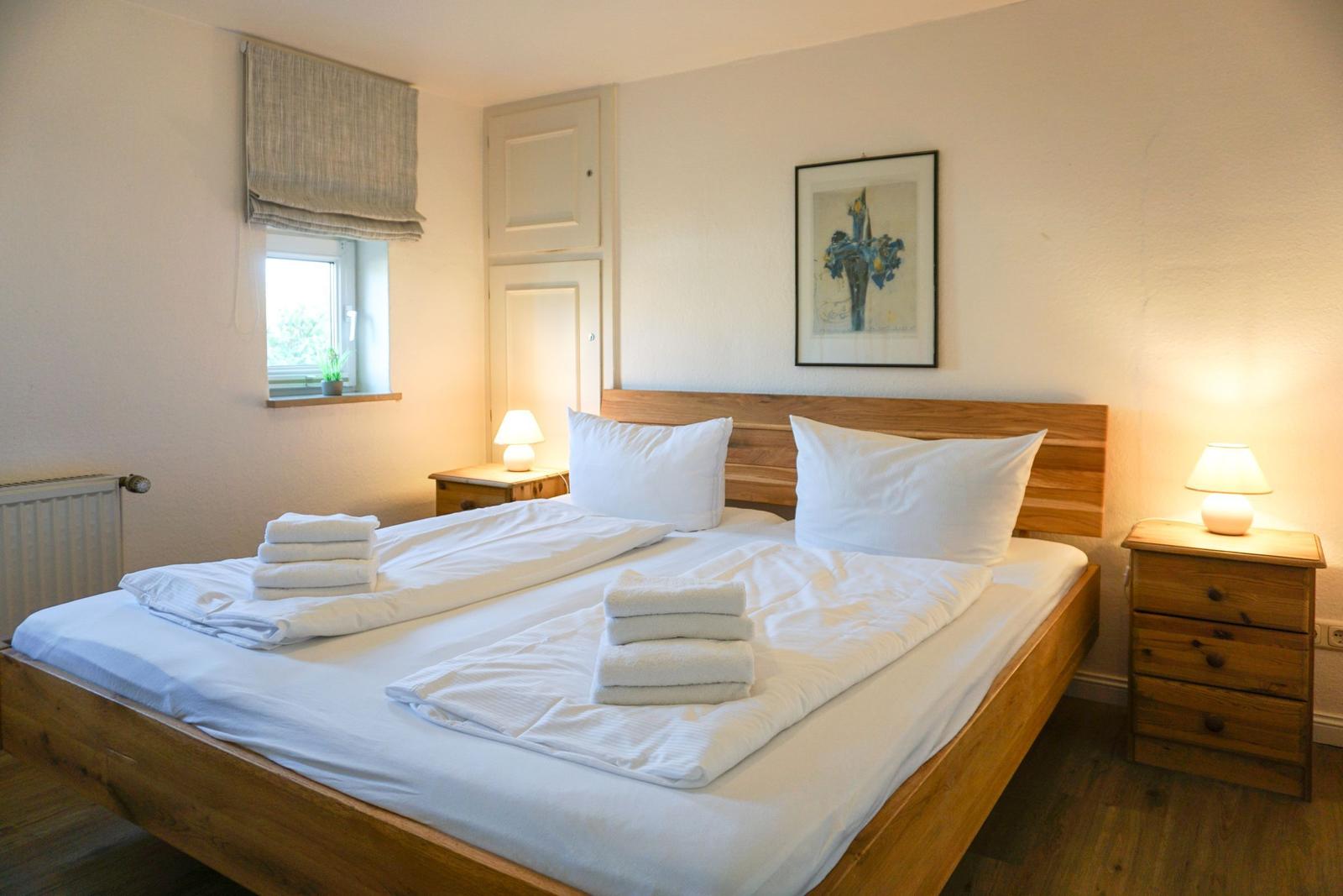 Bedroom with wooden bed, two nightstands, and window with roller blind.