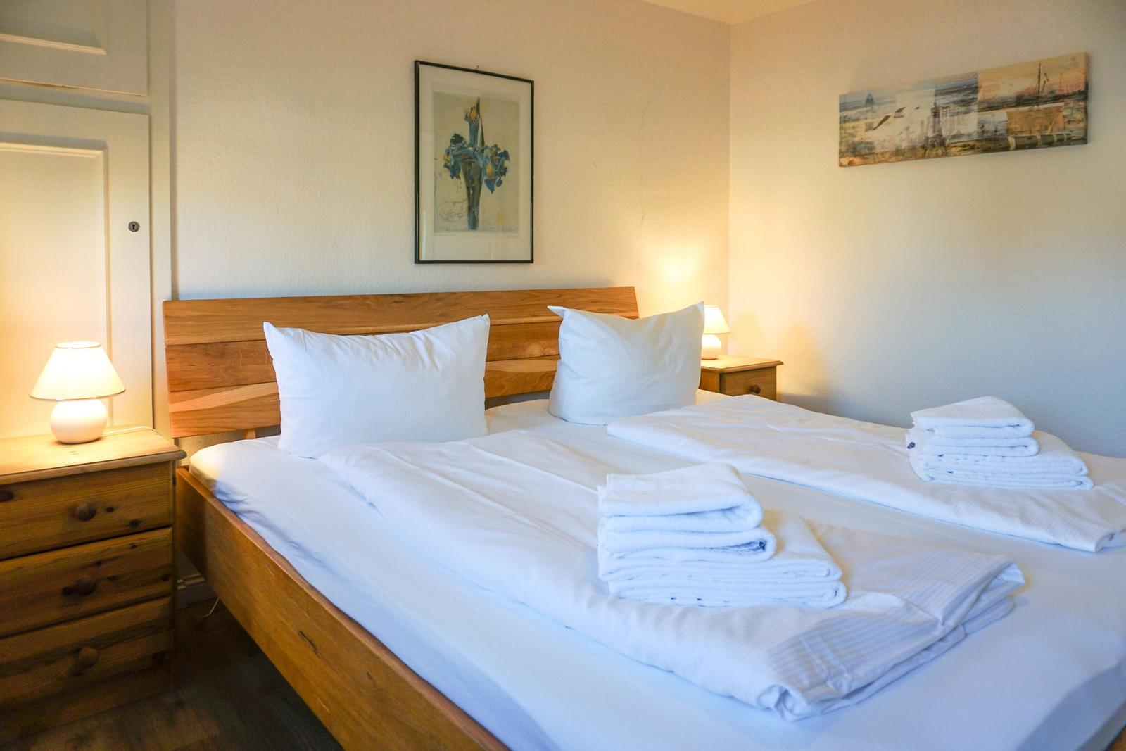 Bedroom with wooden bed, two nightstands, and pictures on the wall.
