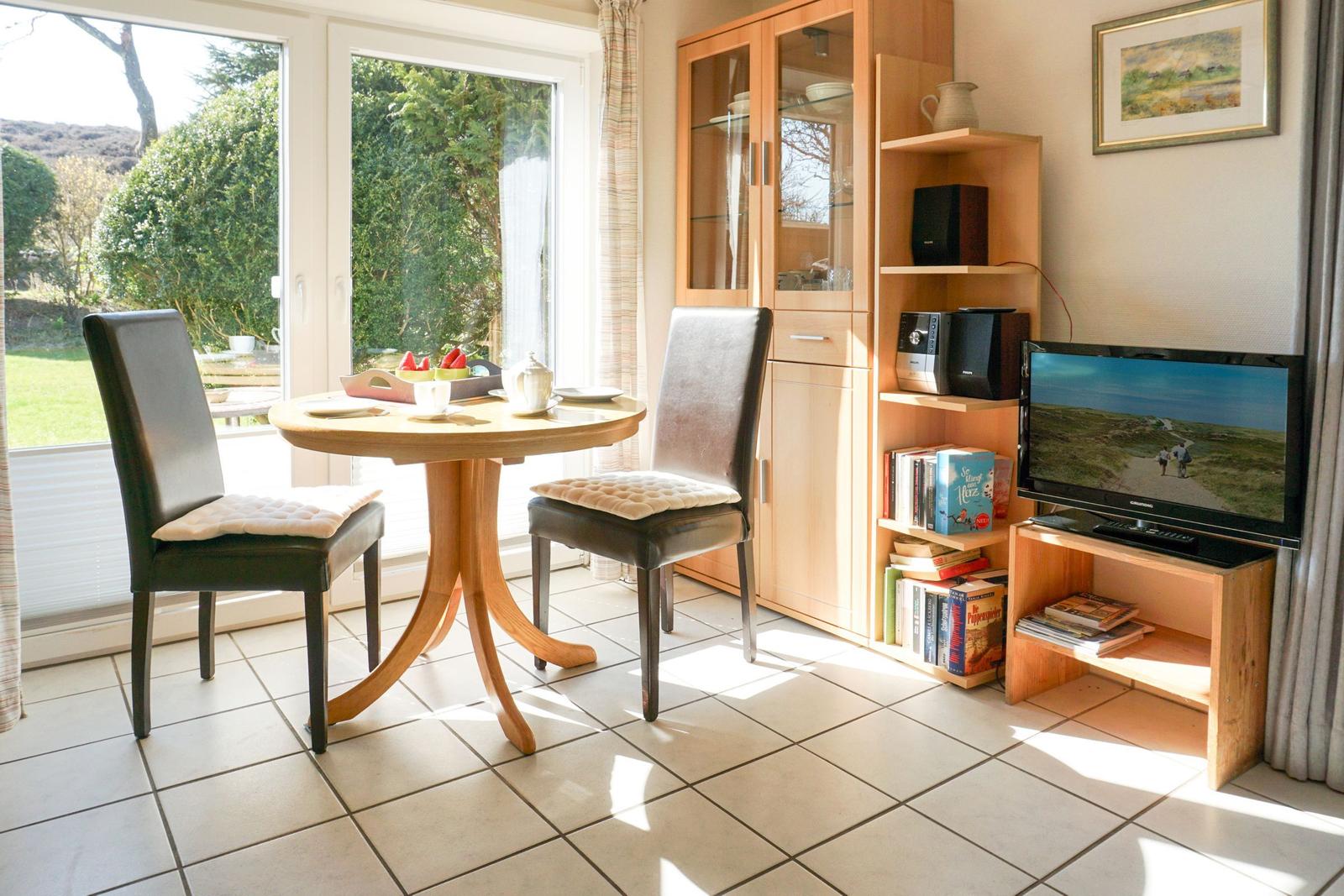Dining room with table, two chairs, and TV. Garden visible outside.