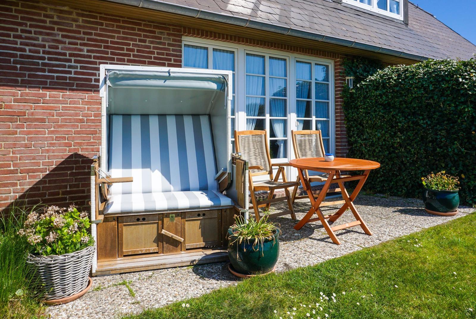Terrace with beach chair, table and chairs beside house wall