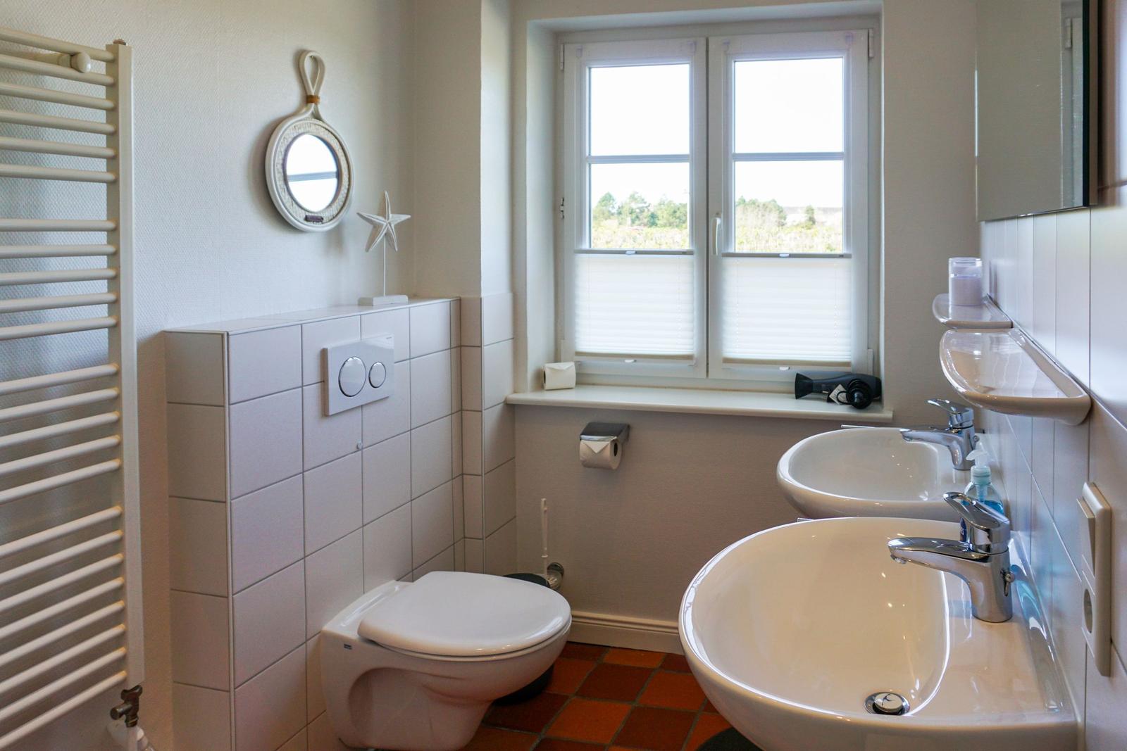 Bathroom with toilet, two sinks, and window