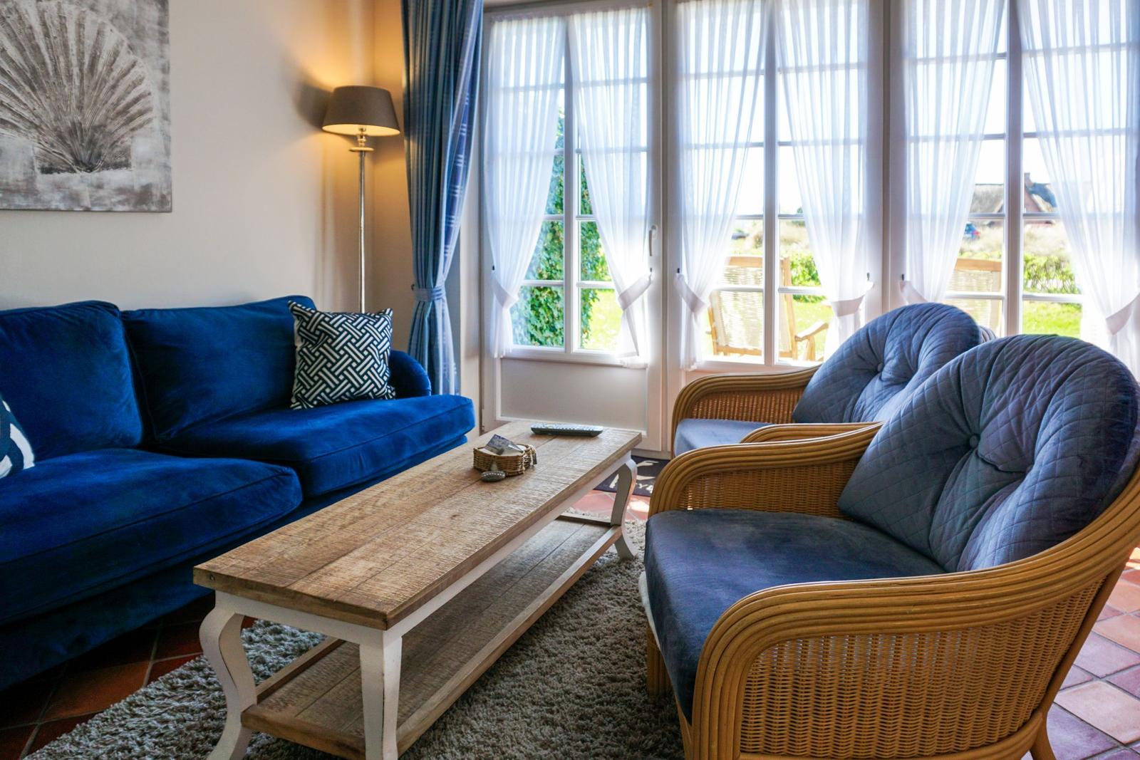 A living room with a blue sofa, two chairs, and large windows.