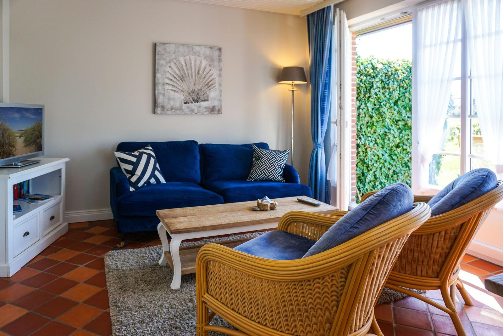 A living room with a blue sofa, two rattan chairs, and a wooden table.