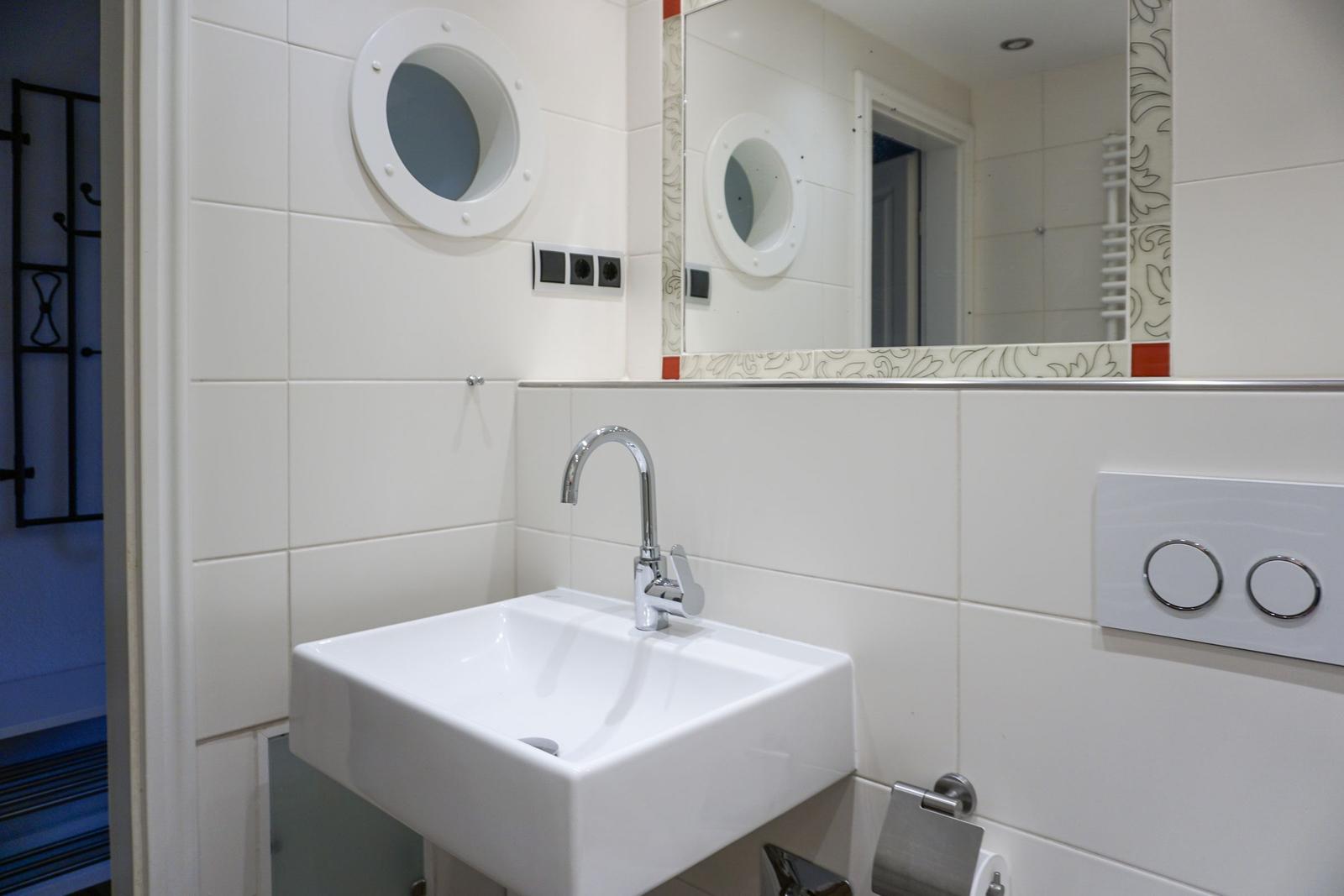 Badezimmer mit Waschbecken, Spiegel und runden Fenster