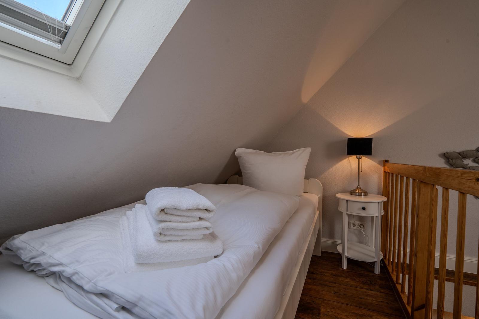 Schlafzimmer mit Dachschräge, Bett, Nachttisch und Fenster