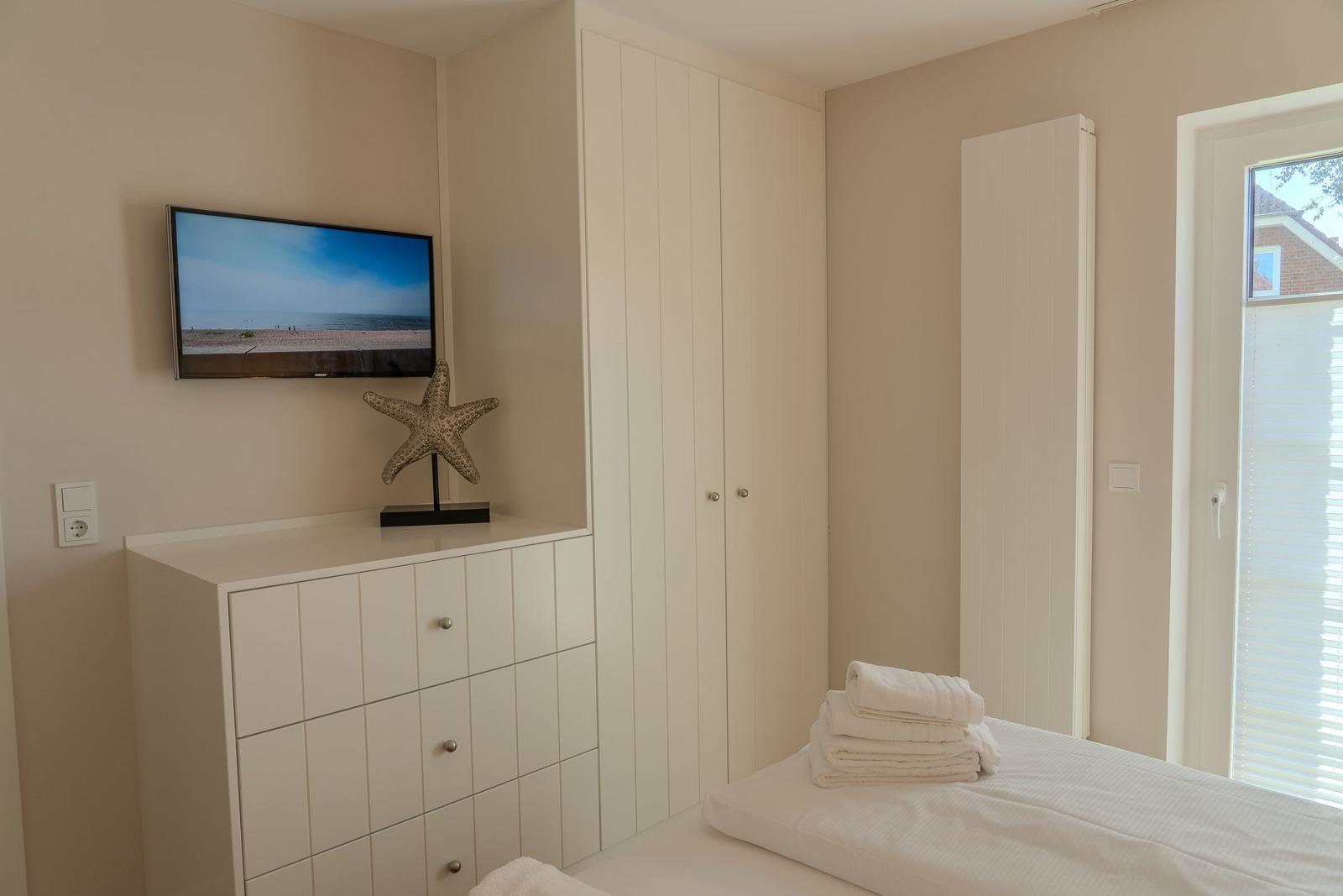 Schlafzimmer mit TV, Kleiderschrank und Fenster