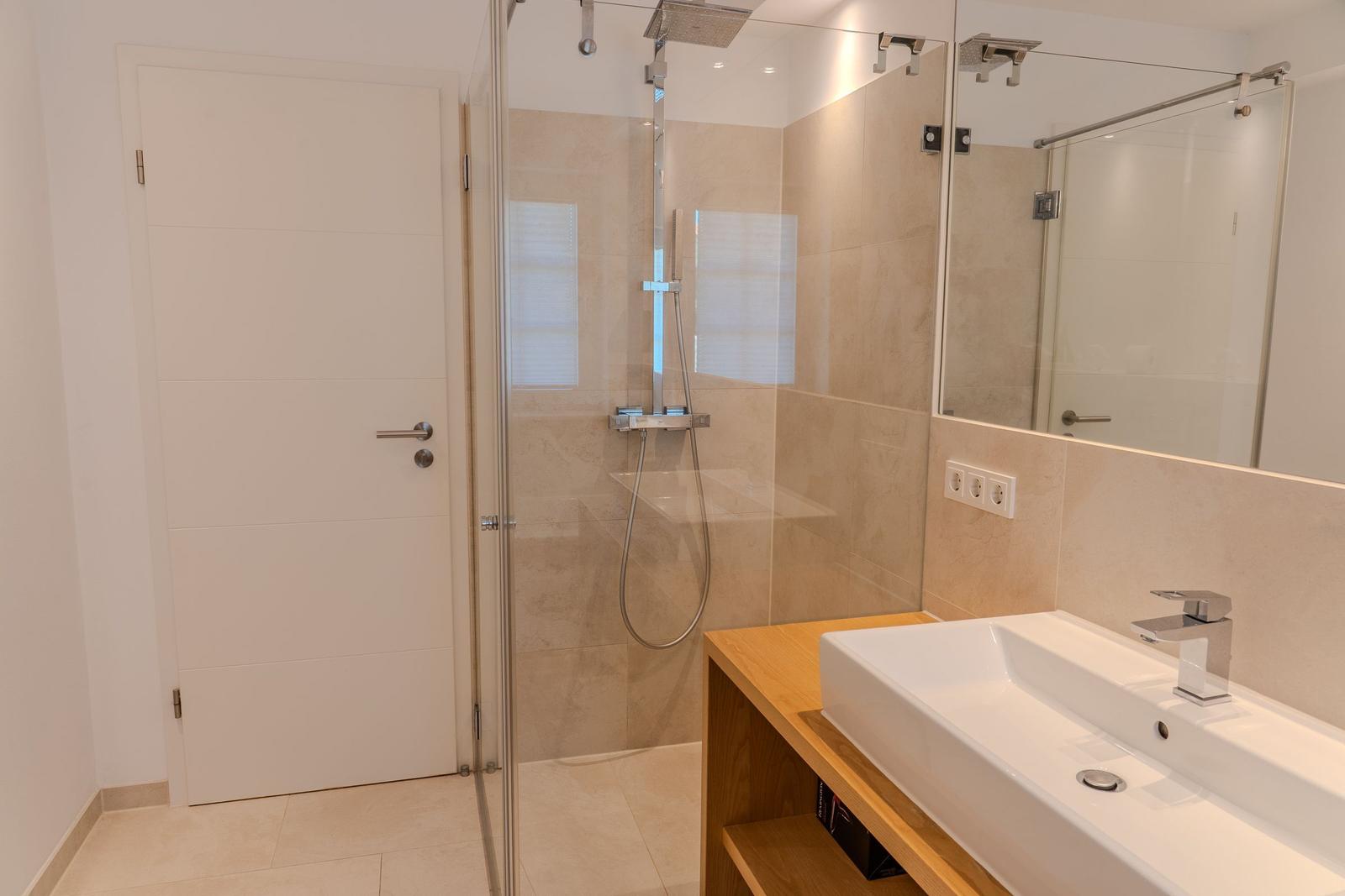 Badezimmer mit Dusche, Waschbecken und Spiegel.