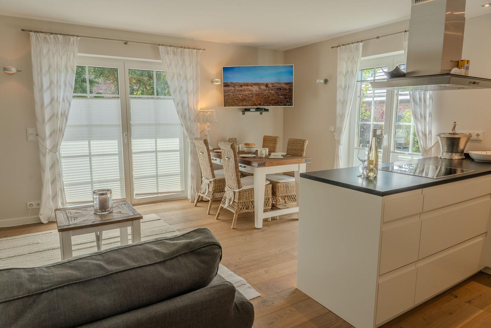 Küche und Esszimmer mit Holzboden und Fenstern. Esstisch mit Stühlen und Fernseher an der Wand.