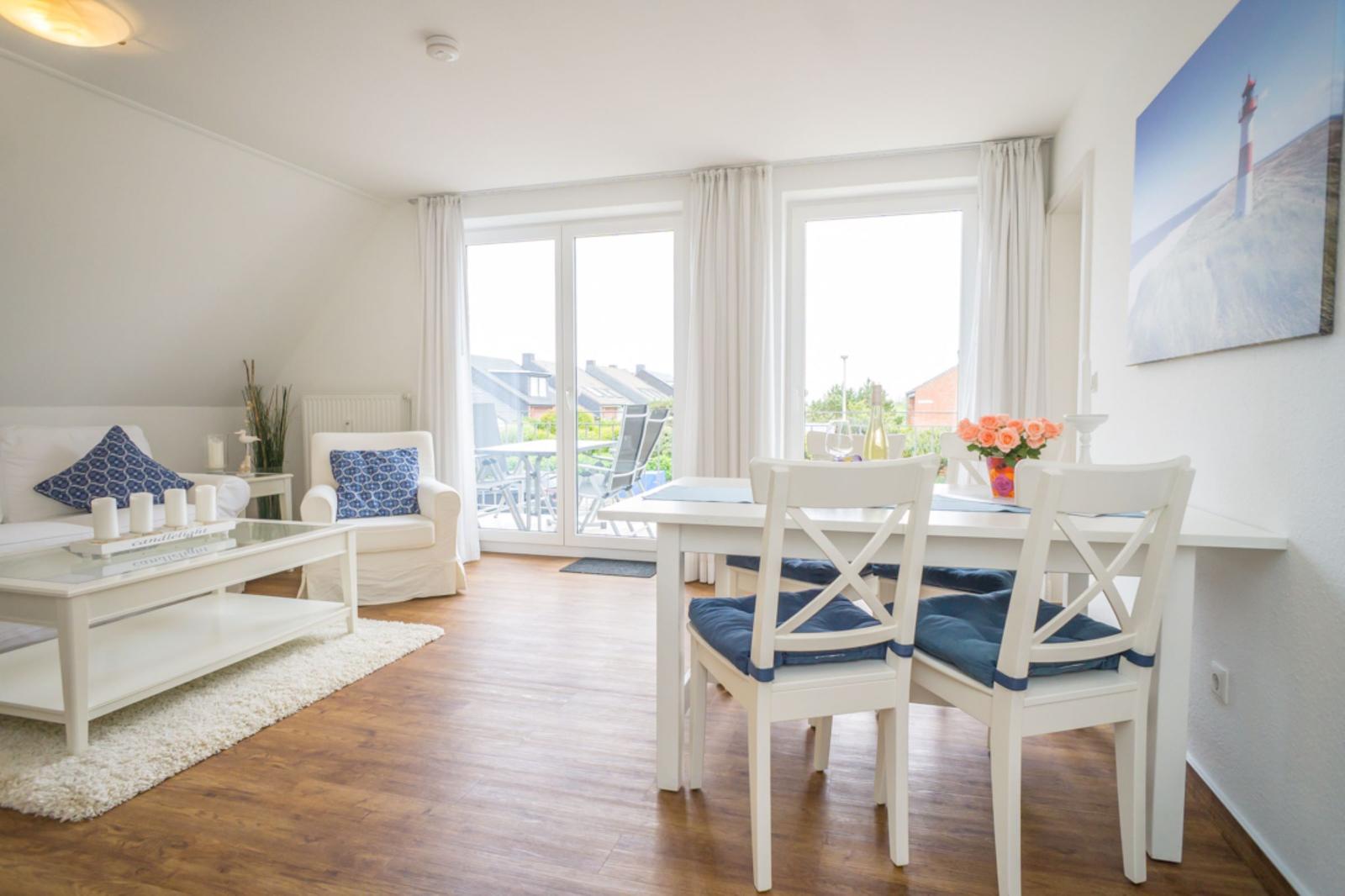 Wohn- und Essbereich mit weißen Möbeln und Blick auf Balkon.