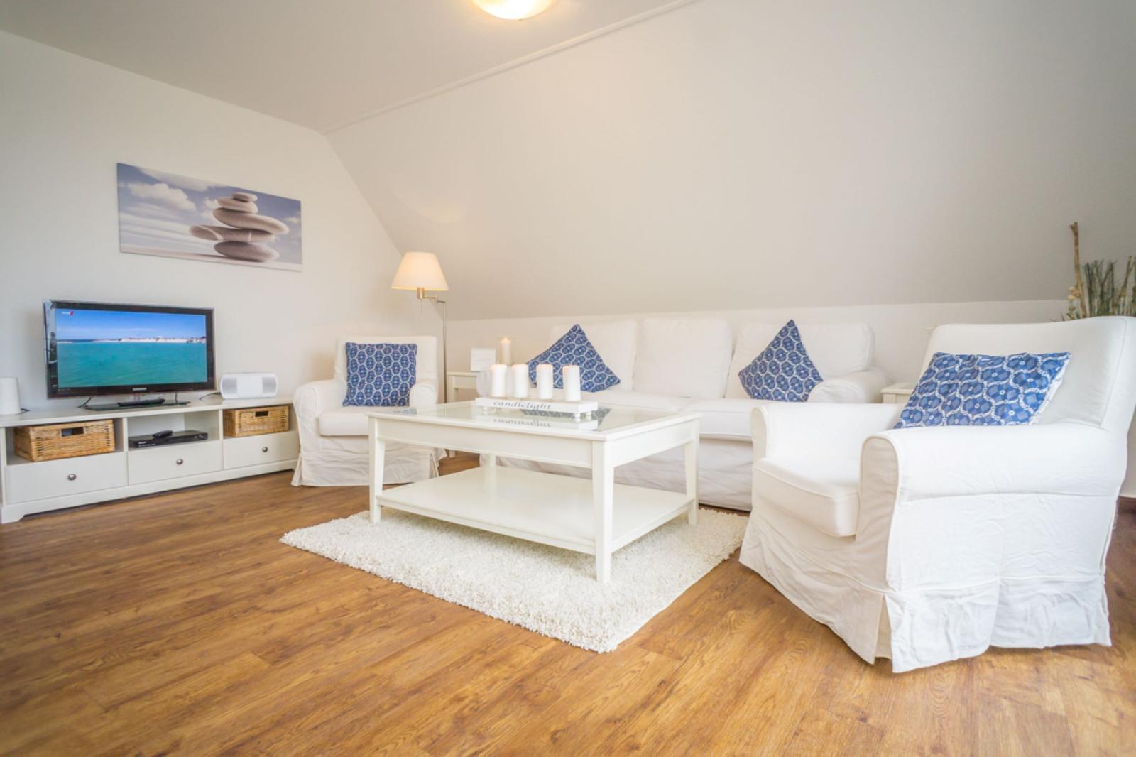Wohnzimmer mit weißem Sofa, Holzboden und Fernseher