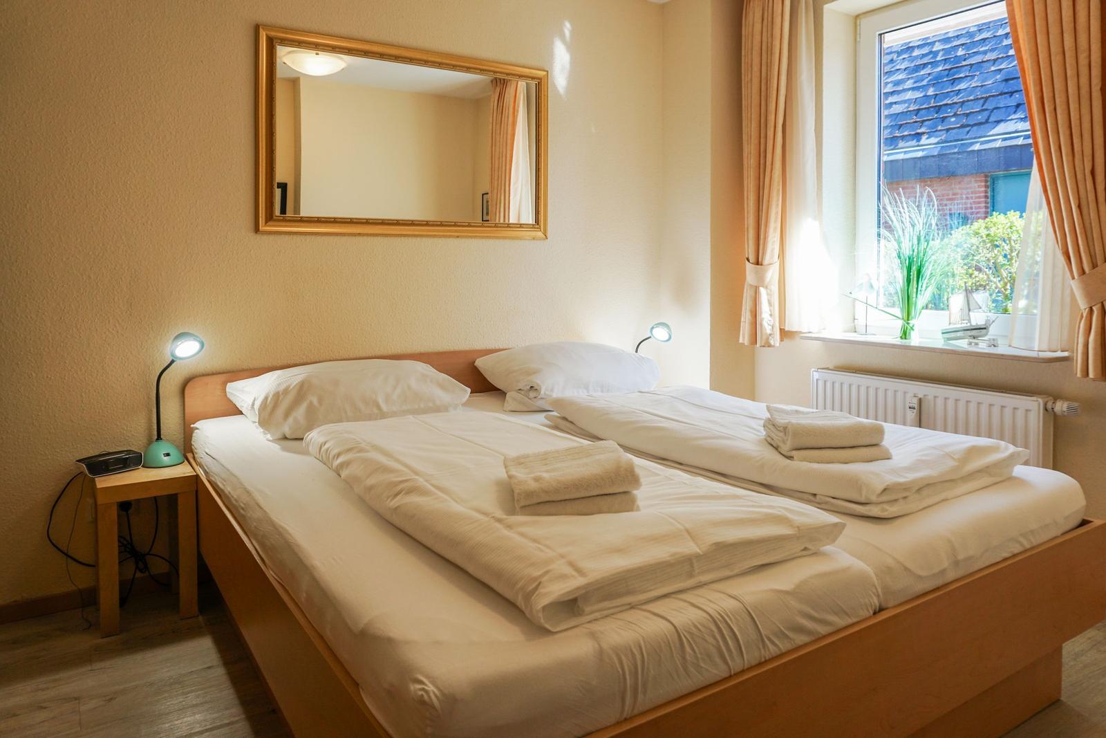 Schlafzimmer mit Doppelbett, Spiegel und Fenster mit Blick.