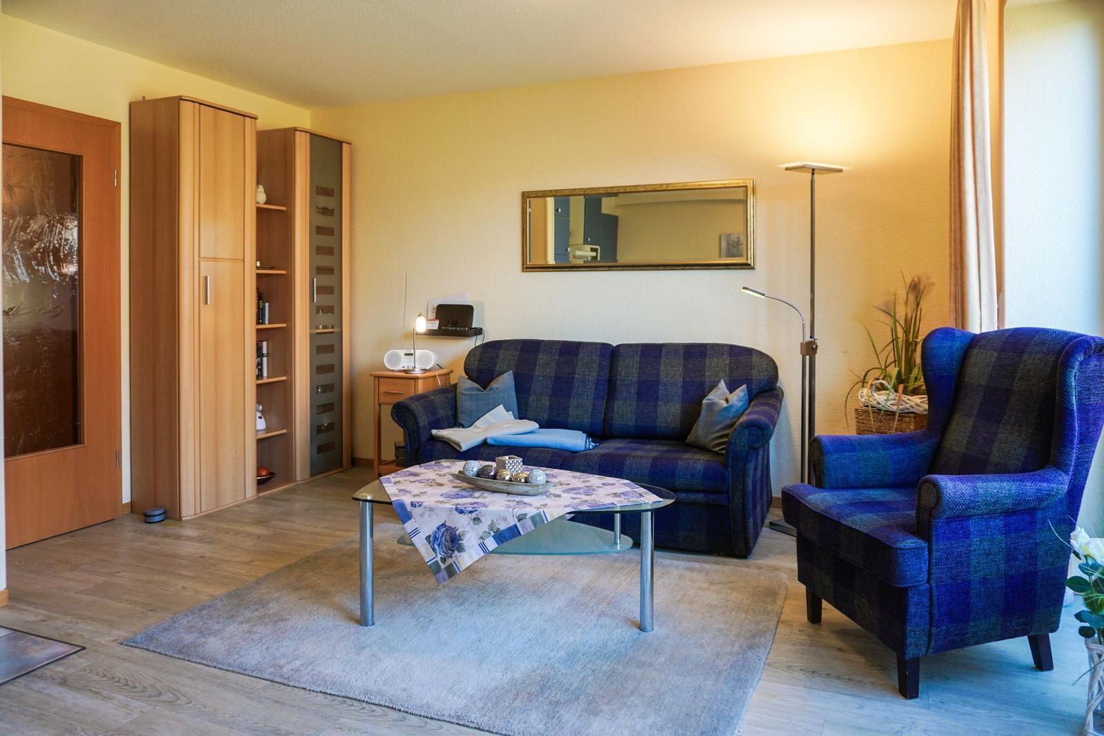 Wohnzimmer mit Sofa, Sessel, Tisch und Schränken.