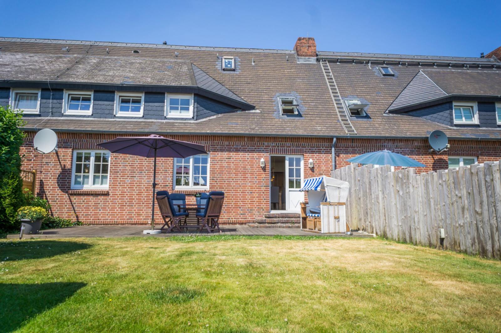Haus mit Garten, Terrasse, Sonnenschirmen und Strandkorb.