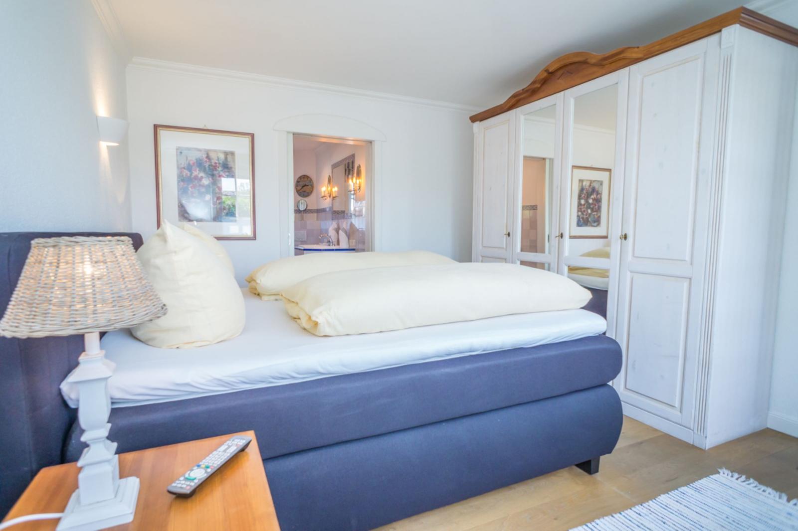 Schlafzimmer mit Bett, Kleiderschrank und Nachttisch.