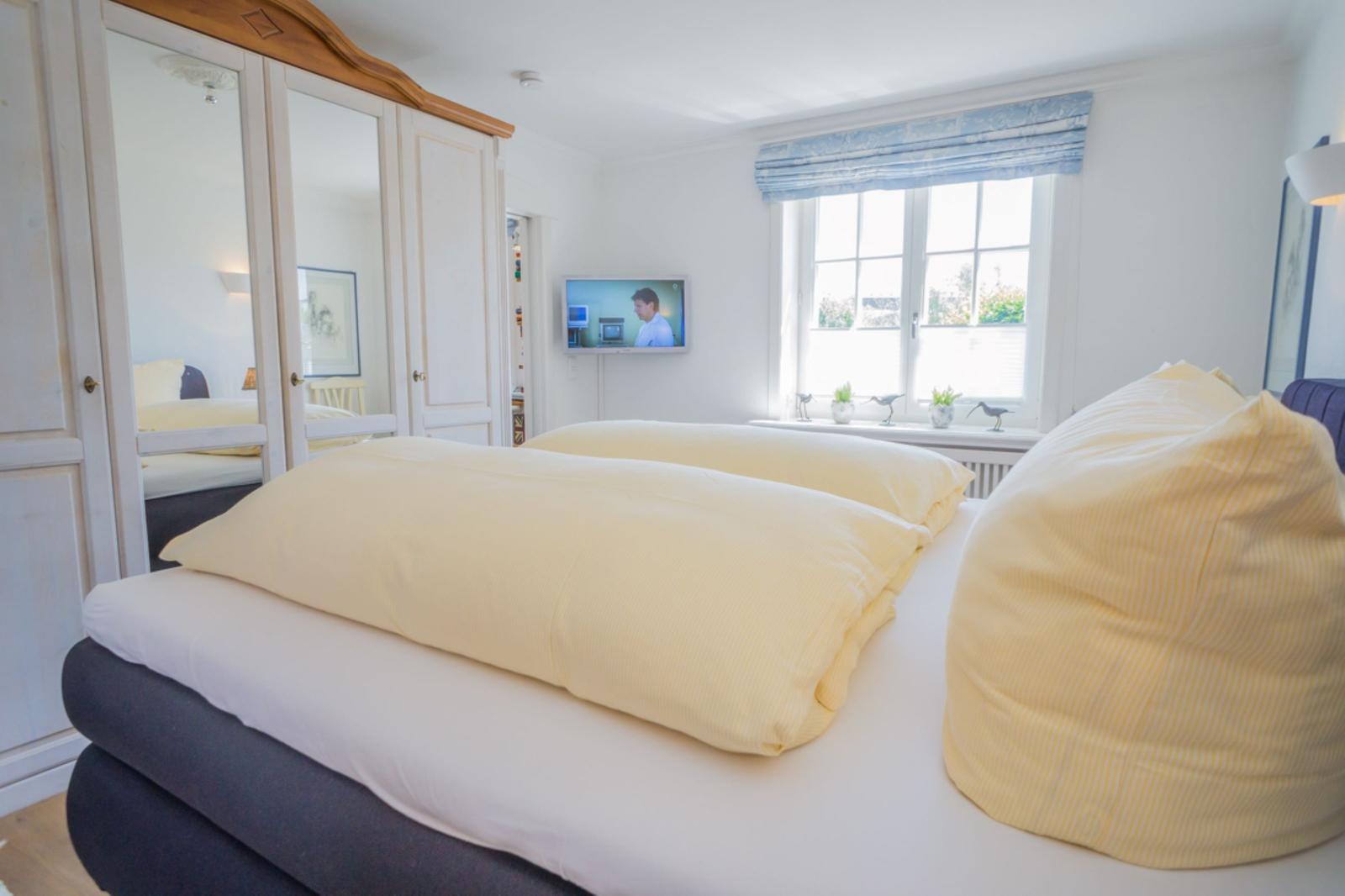 Schlafzimmer mit Doppelbett, Spiegelschrank und Fenster mit Blenden.