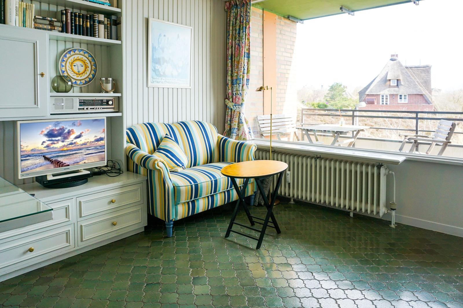 Living area with sofa, TV, and view of balcony