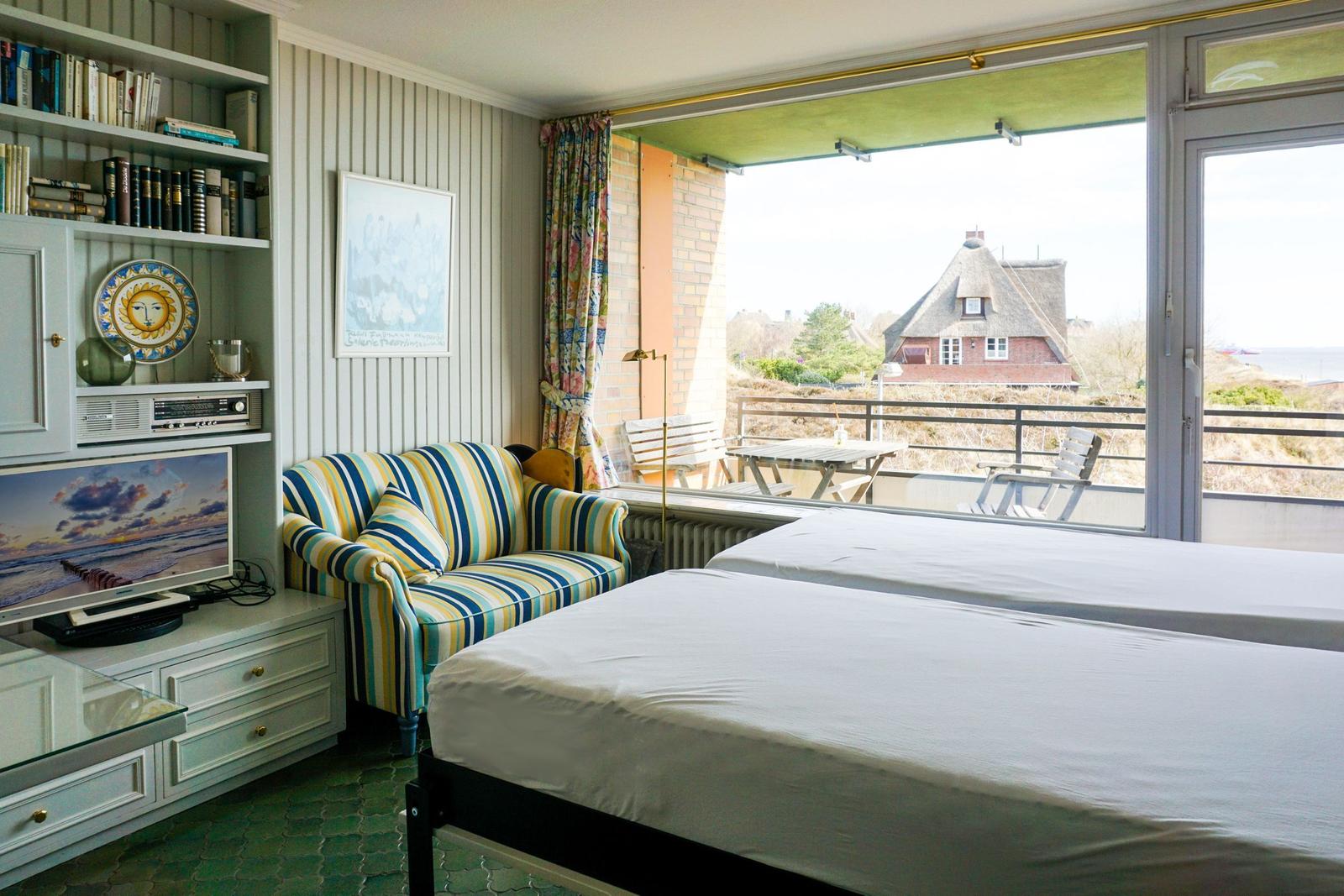 Two beds, sofa, TV, and balcony with sea view.