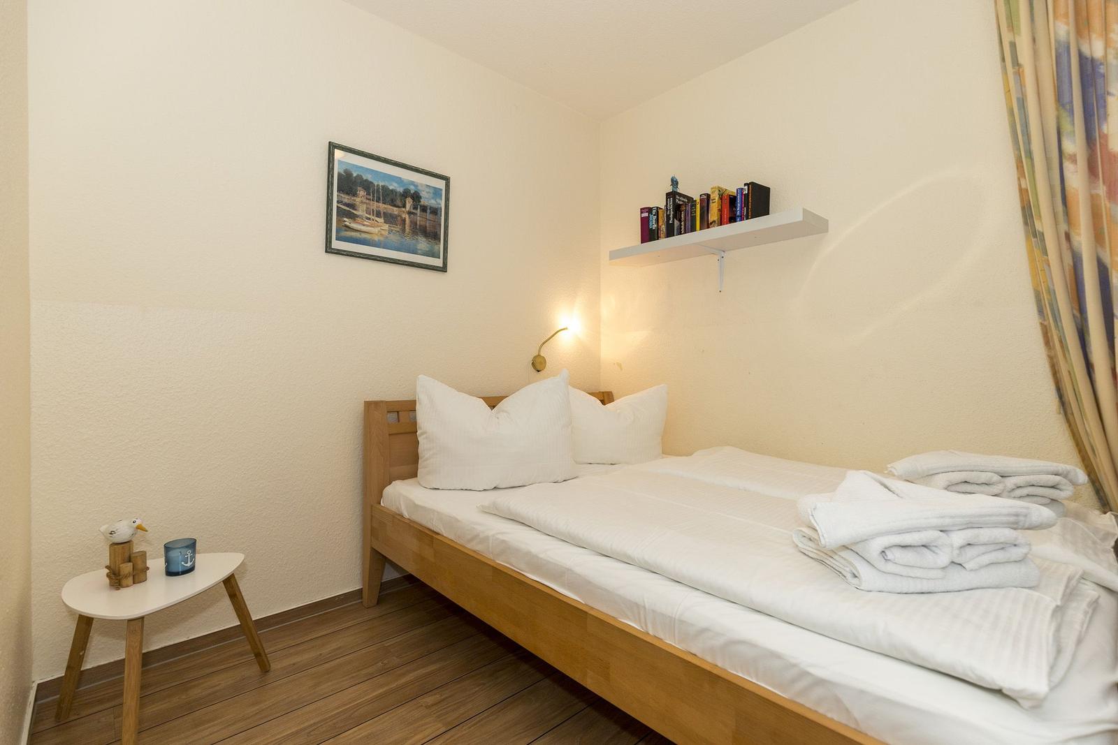 Ein Schlafzimmer mit einem Bett, einer Nachttisch, einem Regal und einem Bild an der Wand.