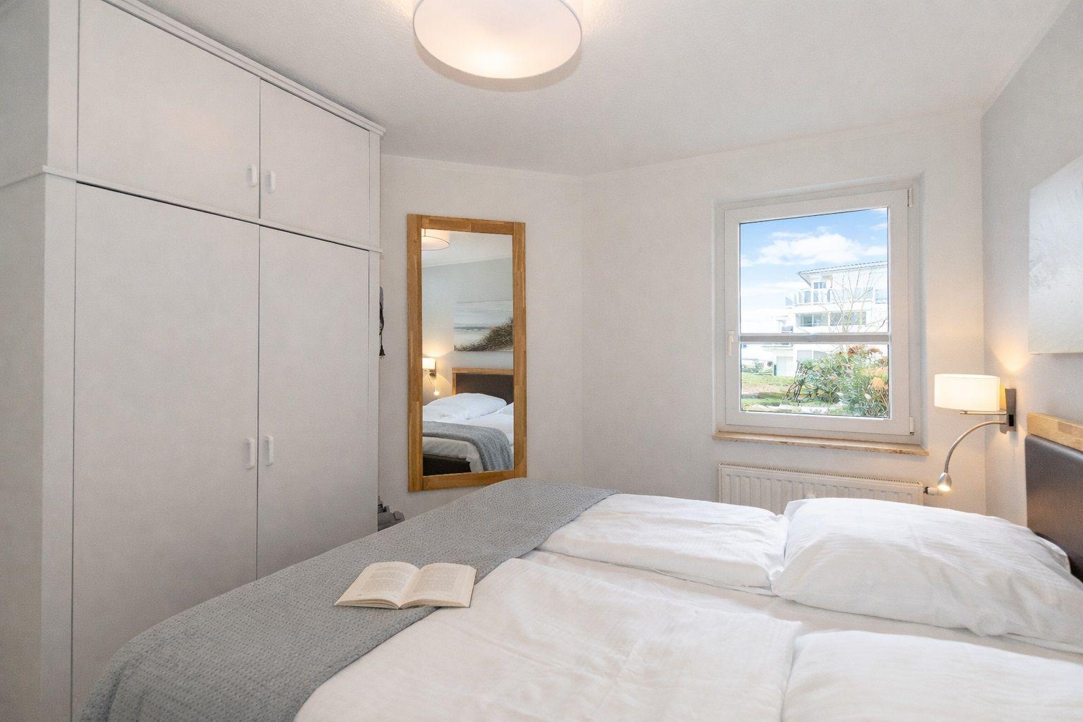 Bedroom with bed, wardrobe, mirror, and window view.