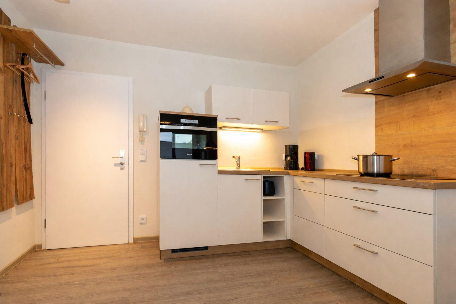 Kitchen with white cabinets, wooden countertop, and built-in oven.