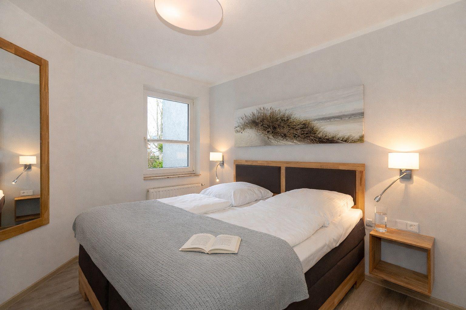 Bedroom with double bed, wall art, nightstand, and window.