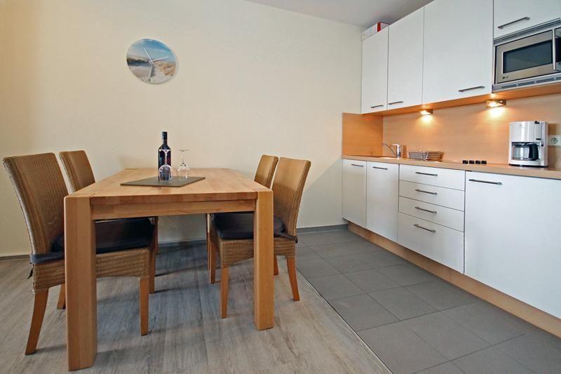 Dining area with table, four chairs, and kitchen with white cabinets.