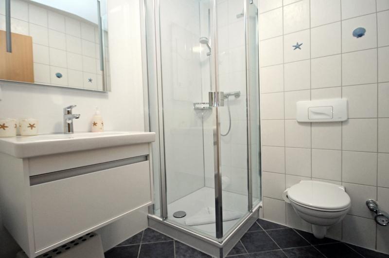 Bathroom with shower, sink, and toilet. Wall tiles with shell and starfish motifs.