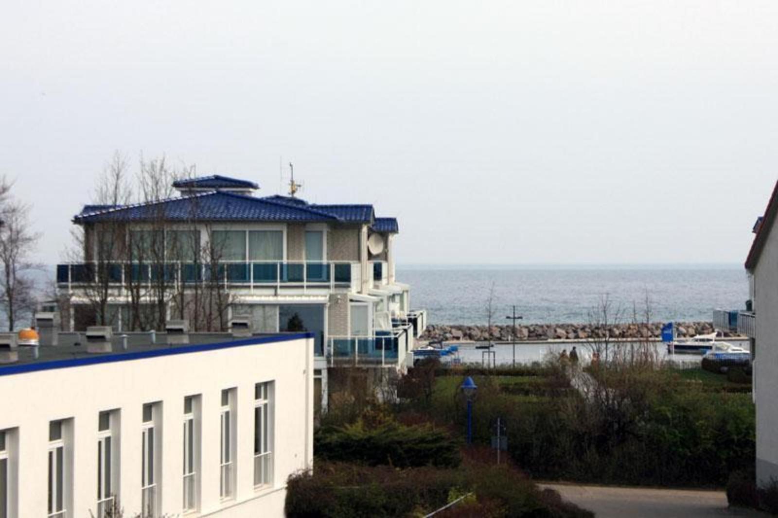 House with balcony and sea view. In background, sea and stone harbor.