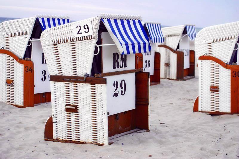 Beach chairs with blue and white awnings stand on sand