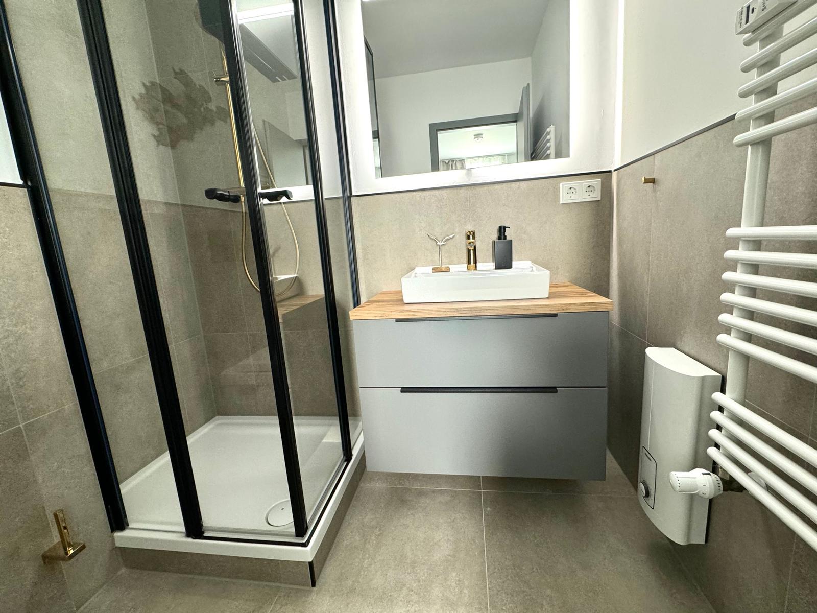 Moderne Badewanne mit Dusche, Waschbecken und Heizkörper.