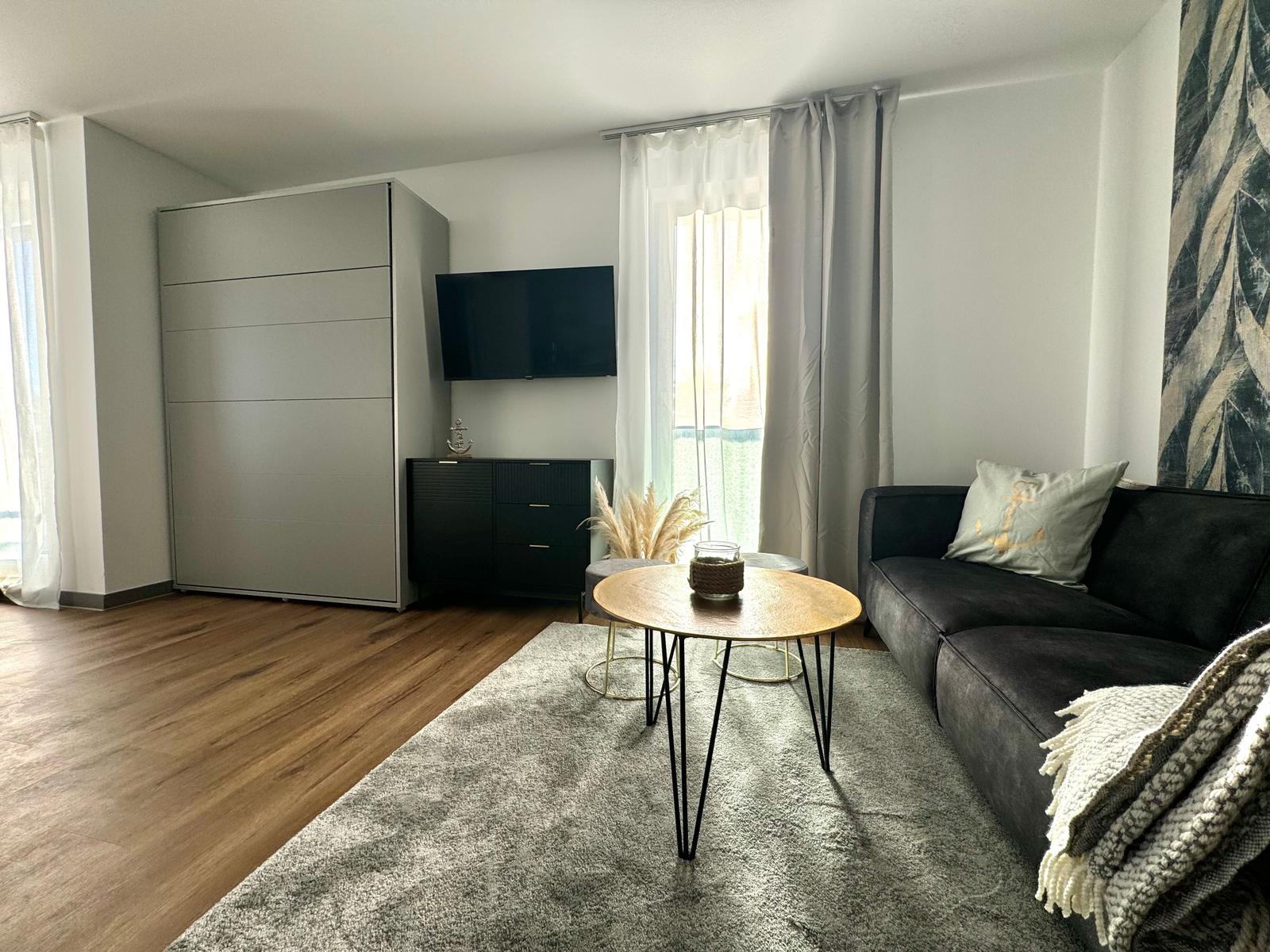 Wohnzimmer mit Sofa, Couchtisch und Fernseher an der Wand.