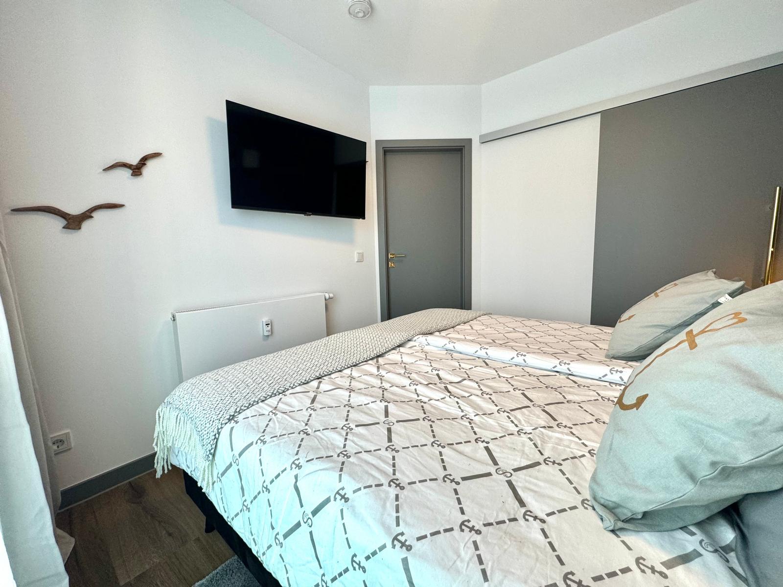 Schlafzimmer mit Bett, Fernseher und Kleiderschrank.