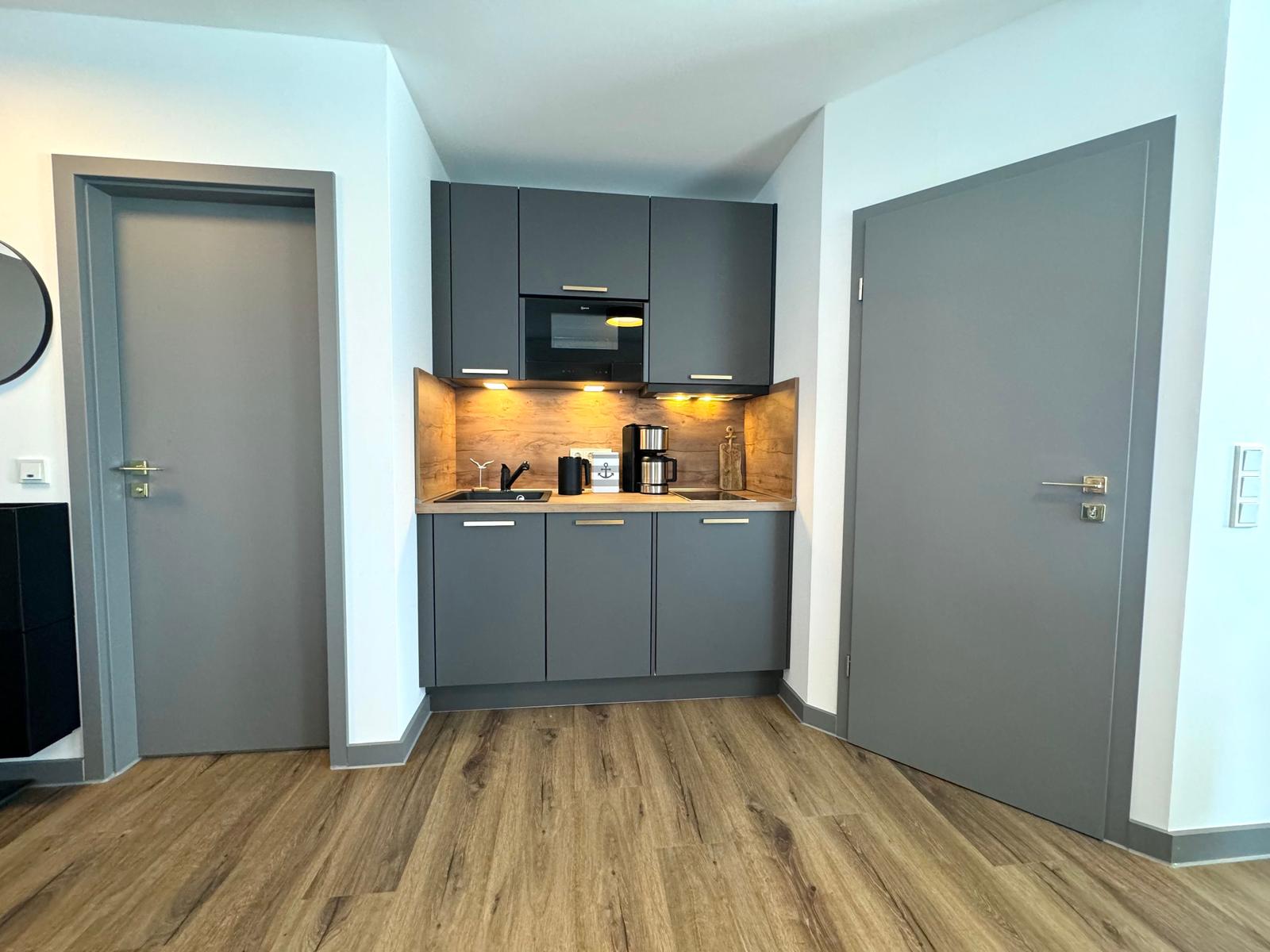 Küche mit grauen Schränken, Holzoptik und integriertem Mikrowellenherd.