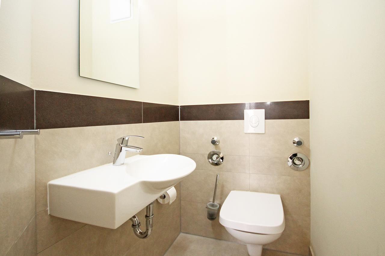 Badezimmer mit Waschbecken, Toilette und Spiegel an der Wand.