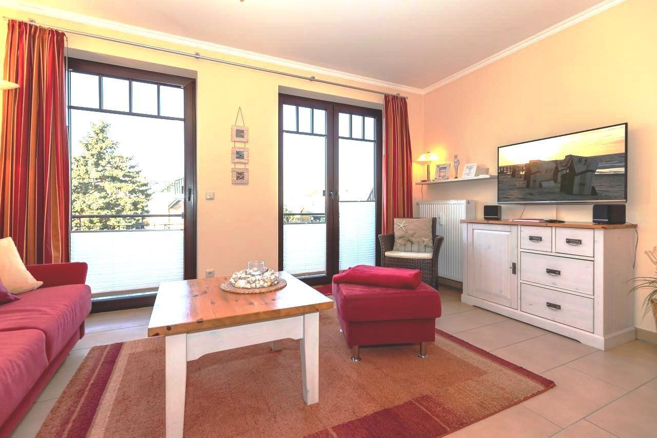 Wohnzimmer mit rotem Sofa, Holztisch und TV auf Schrank