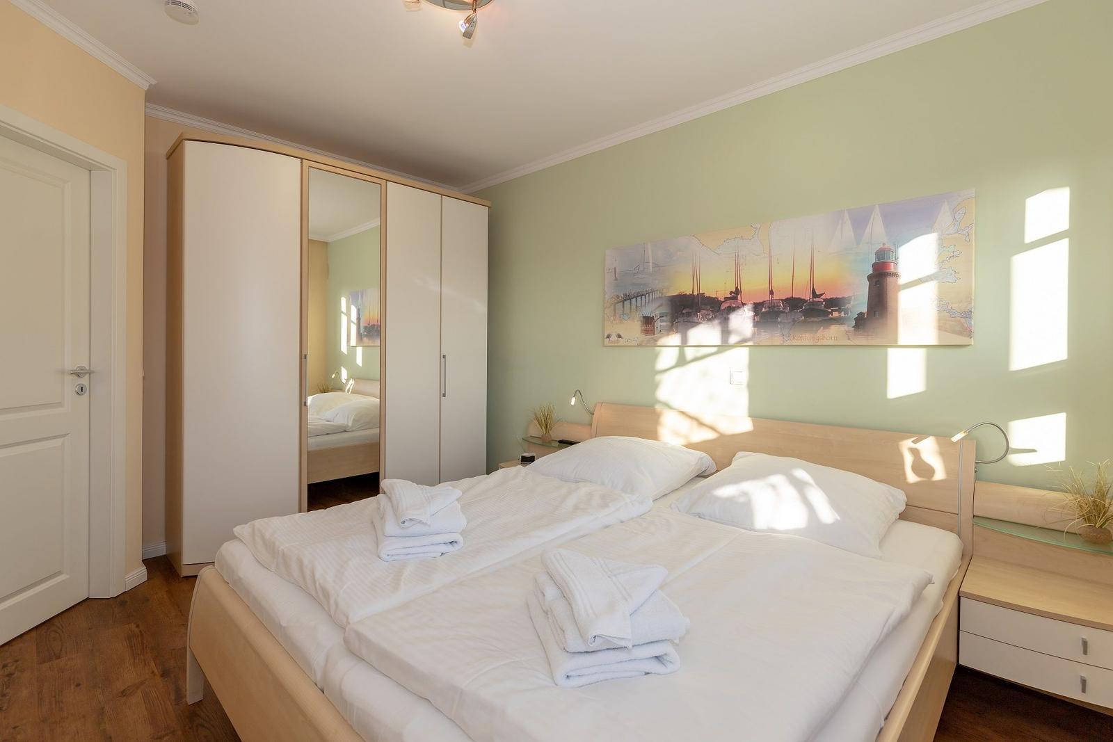 Schlafzimmer mit Doppelbett, Kleiderschrank und Wandbild.