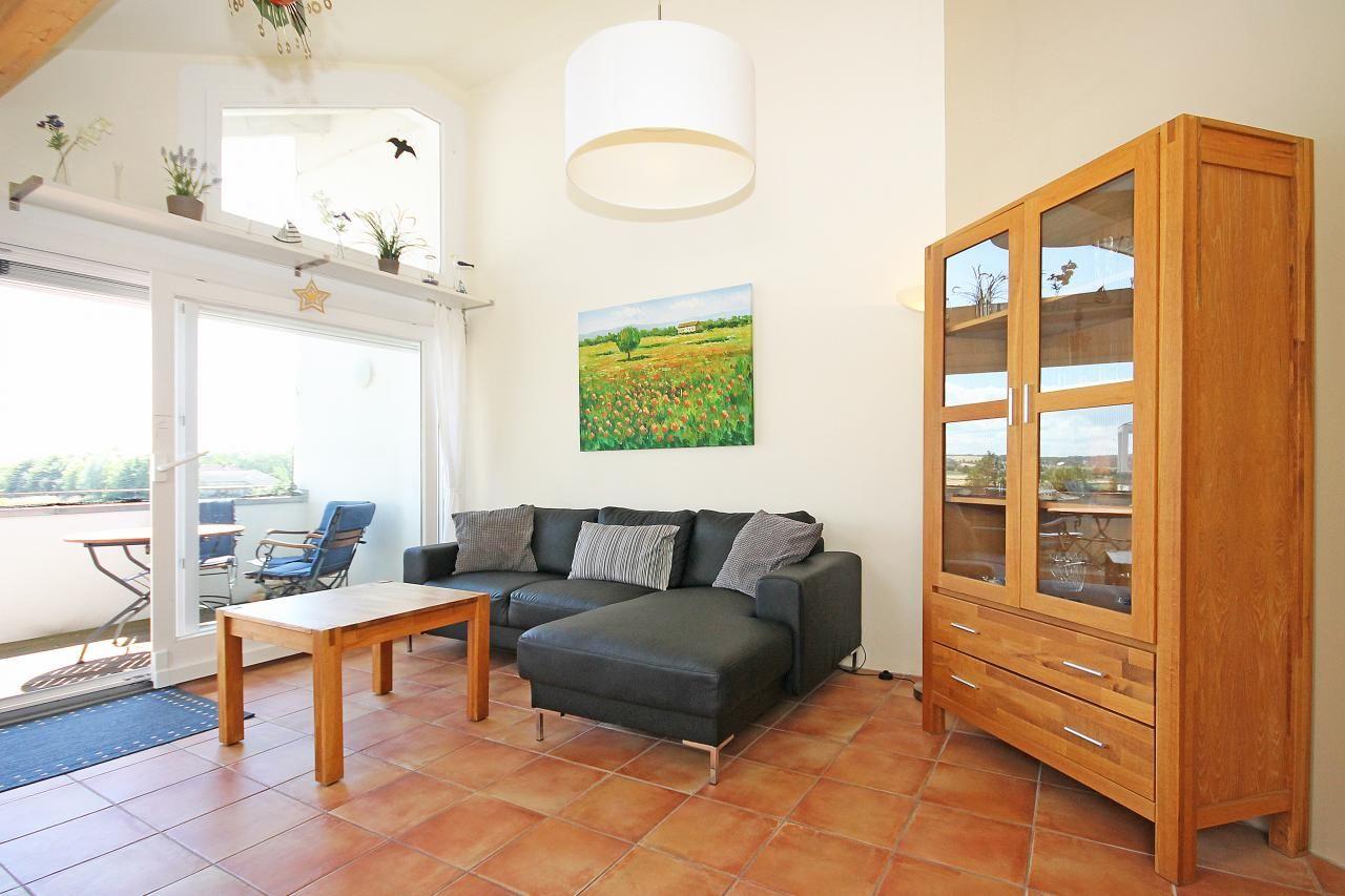 Wohnzimmer mit Sofa, Holztisch und Glaswand-Schrank. Terrasse mit Blick auf die Landschaft.