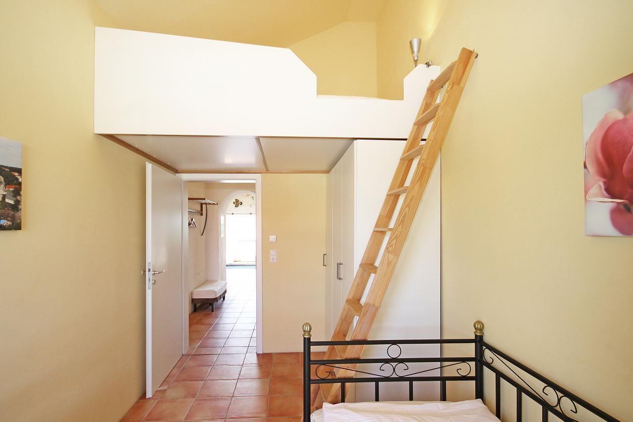 Ein Schlafzimmer mit Doppelbett und Treppenhaus zur oberen Etage.