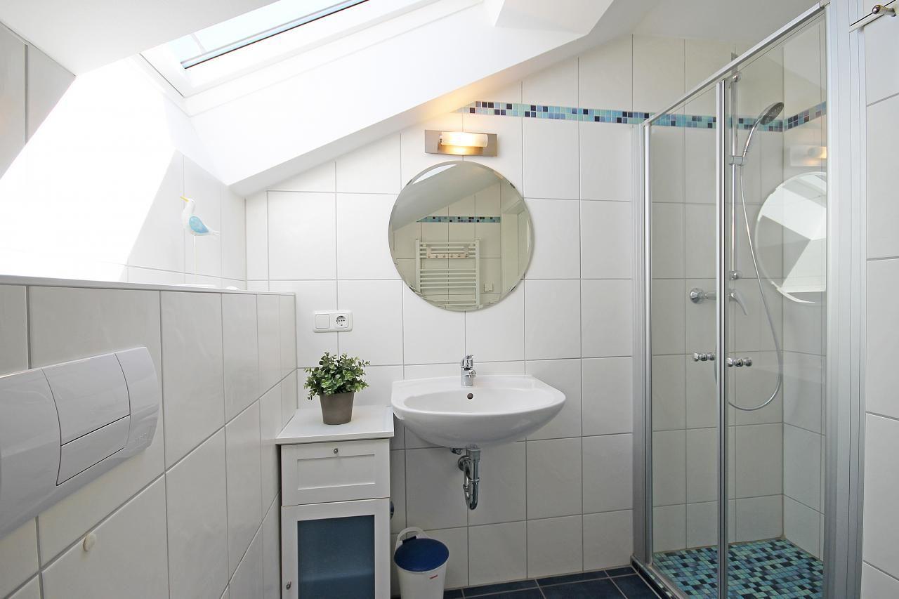 Badezimmer mit Dusche, Waschbecken und Dachfenster.