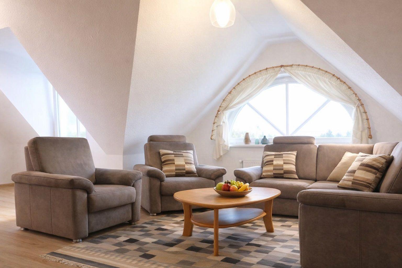 Wohnzimmer mit Sitzgruppe, Holztisch und Rundfenster unter Dachschrägen.