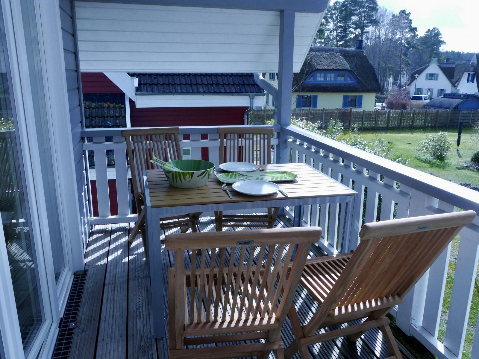 Terrasse mit Tisch und Stühlen, Blick auf Garten und Häuser.