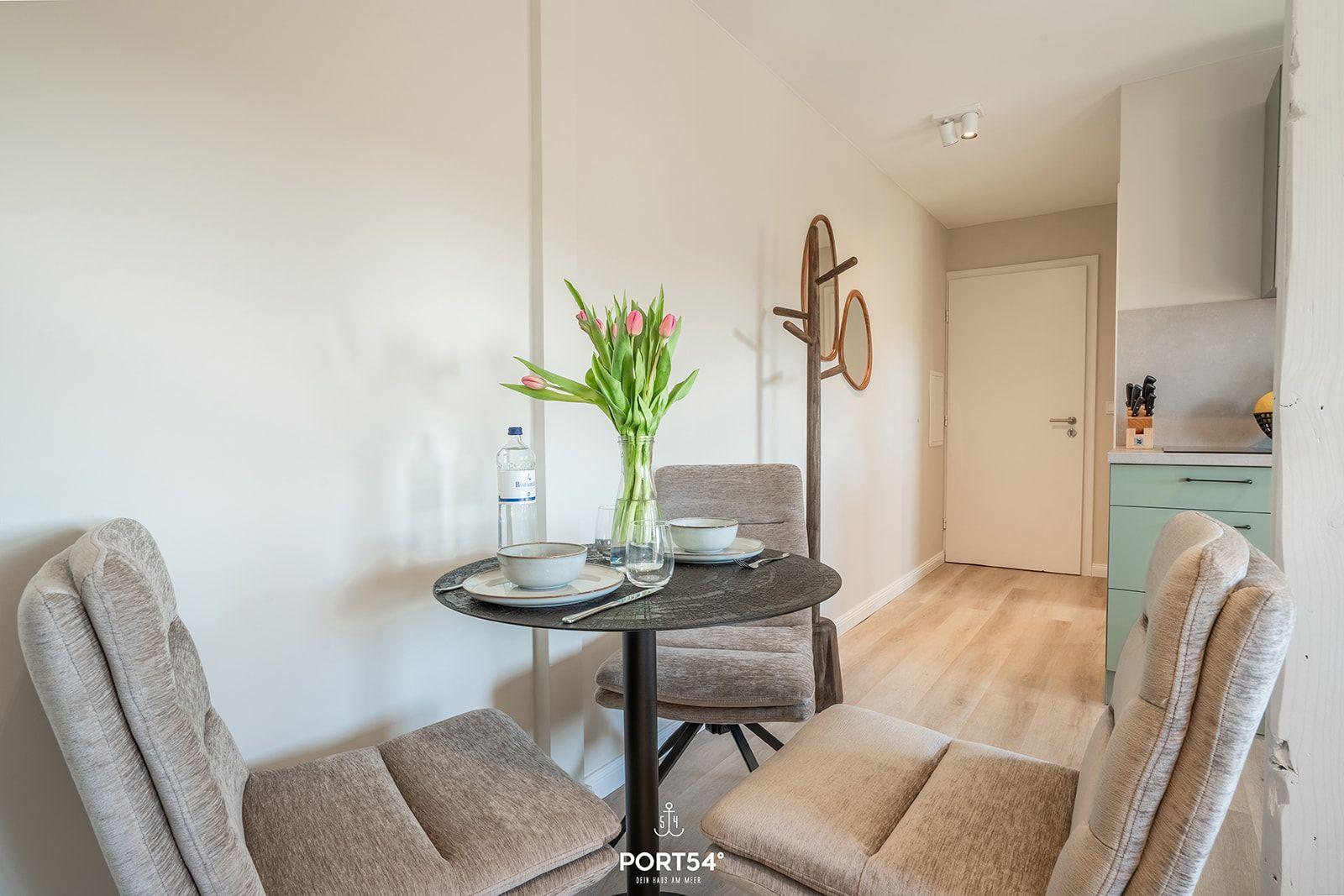 Dining area with round table, three chairs, and flower bouquet