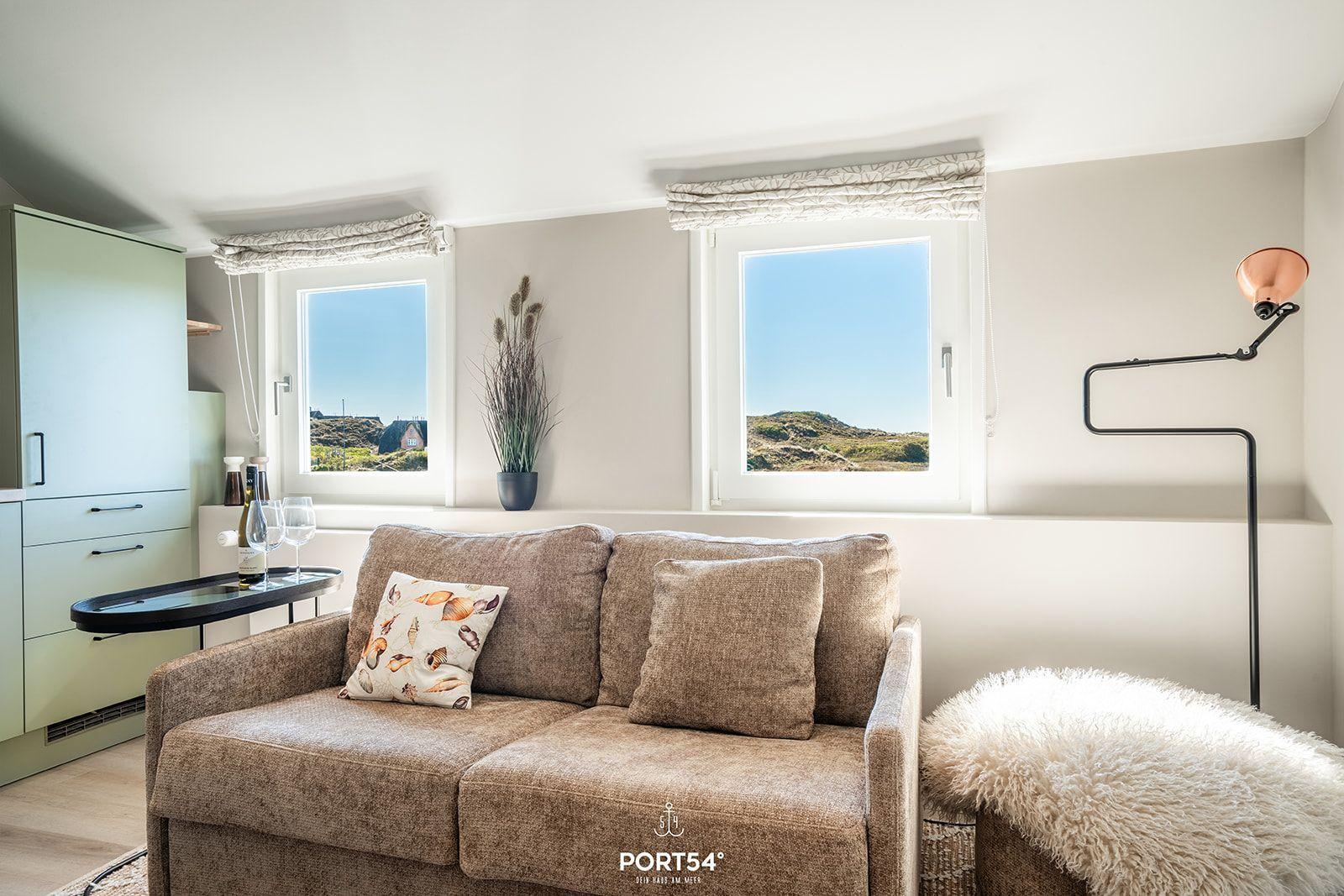 Living room with sofa, windows, and kitchen area.